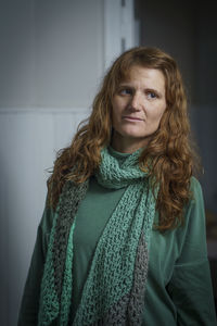 Portrait of young woman standing against wall