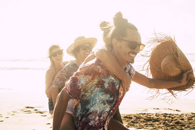 Cheerful people walking on beach during sunset