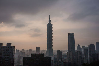 Skyscrapers in city against cloudy sky