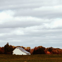 View of white barn on field in autumn with overcast sky