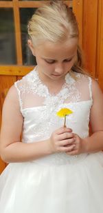 Girl holding yellow flower during wedding ceremony