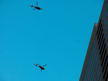 Low angle view of airplane flying against clear blue sky