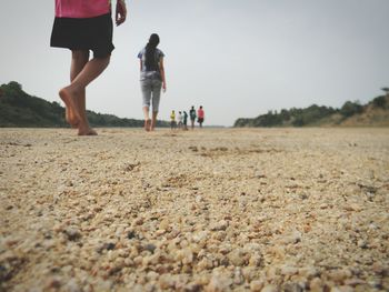 Surface level view of people on sand at beach against sky