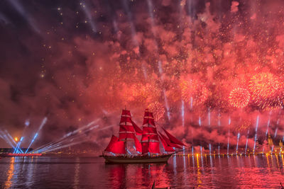 Firework display over river against sky at night