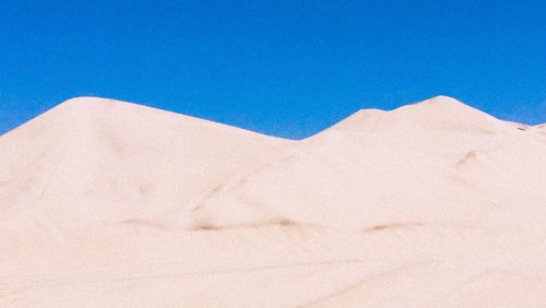 Scenic view of desert against clear blue sky