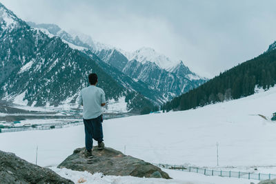 Rear view of man walking on snowcapped mountain