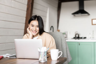 Businesswoman using laptop while sitting on table