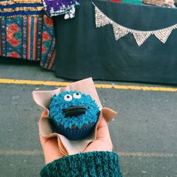 Close-up of cropped hand holding cupcake on road