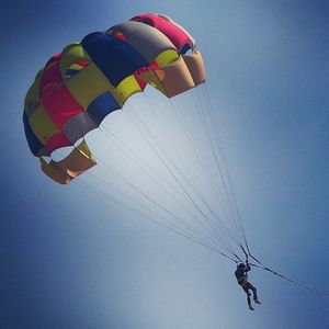 Low angle view of person paragliding against clear sky