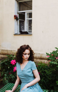 Beautiful teenage girl sitting against plants