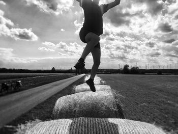 Rear view of man standing on field against cloudy sky
