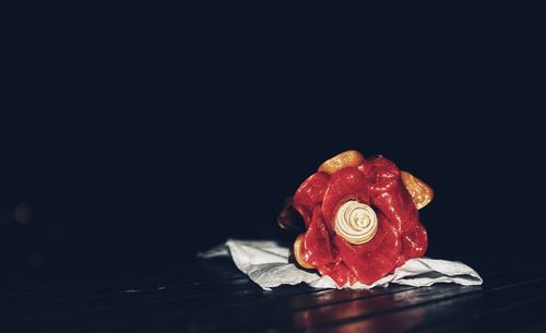 Close-up of red rose on table against black background