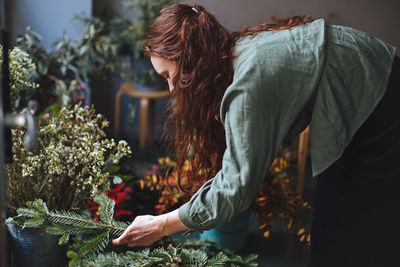 Side view of woman holding plant decoration during christmas