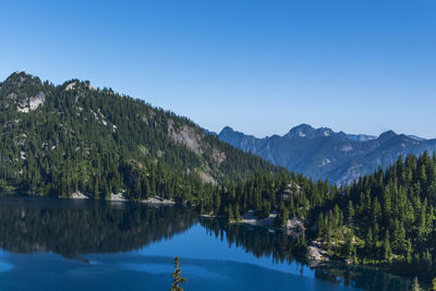 Snow lake placid morning water blue sky mountains.