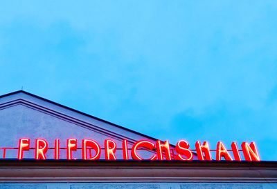 Low angle view of illuminated sign against blue sky