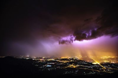 Aerial view of illuminated city against sky at night