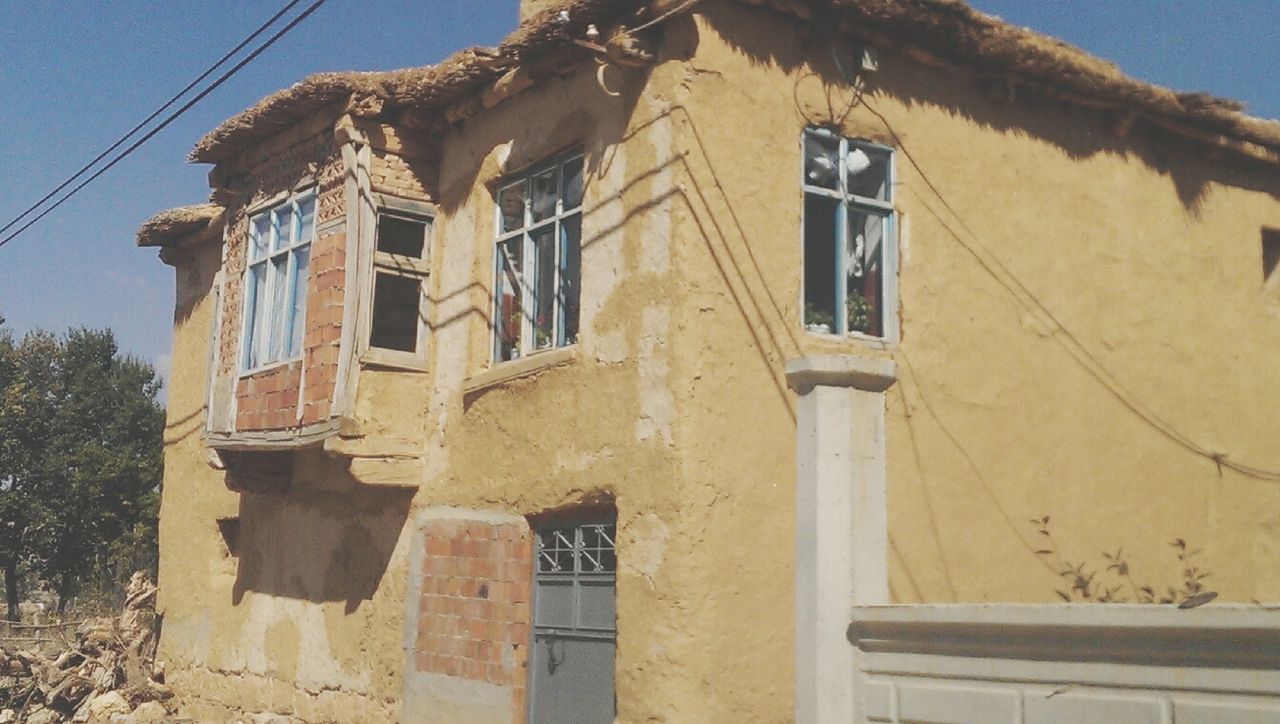 architecture, building exterior, built structure, window, low angle view, residential structure, residential building, house, old, building, clear sky, weathered, day, wall - building feature, abandoned, sky, outdoors, no people, power line, sunlight