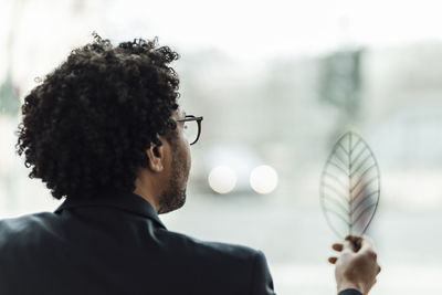 Rear view of man holding eyeglasses