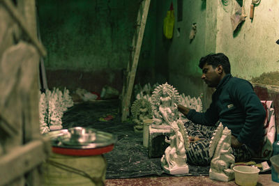 Side view of young man sitting on plants