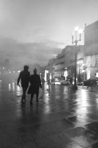 Rear view of people walking on street in rain