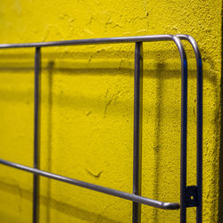 Metallic railing against yellow wall