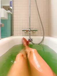 Personal perspective view woman legs in bathtub with colorful salt
