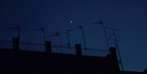 Low angle view of silhouette communications tower against sky at night