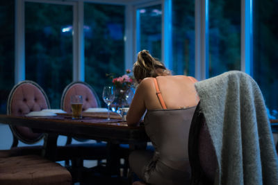 Rear view of woman sitting on table at restaurant