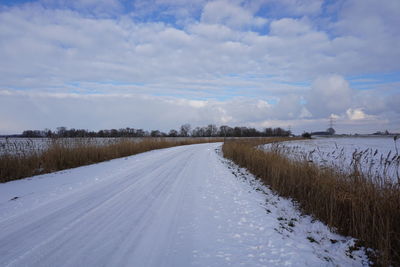 Road amidst snow covered land against sky