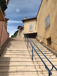 Low angle view of staircase amidst buildings against sky