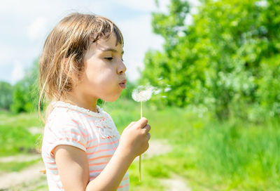 Cute girl blowing dandelion seed