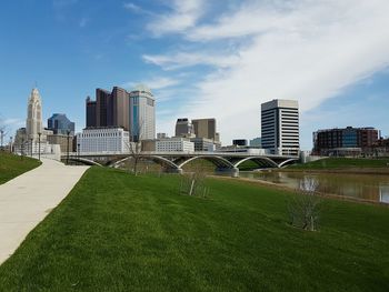 Skyscrapers by river against sky