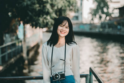 Portrait of young woman standing against railing