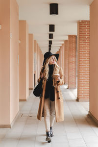 Full length of woman standing in corridor of building