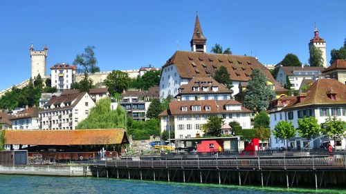 Buildings by river against sky in city