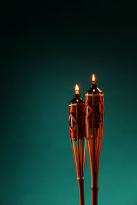 Close-up of illuminated tiki torches against green background