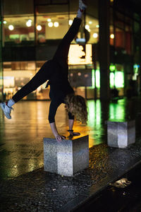 Full length of woman doing handstand on street at night