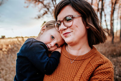 Content toddler hugging his smiling mom outside on an autumn evening