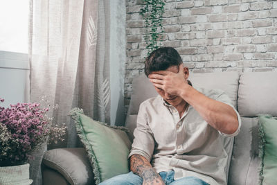 Young man sitting on sofa at home