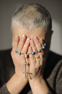 Mature woman with a rosary in her hands and short hair covering her face