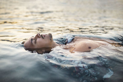 Young man with eyes closed floating in water