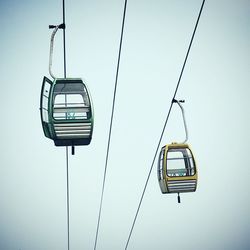 Low angle view of overhead cable cars against clear sky