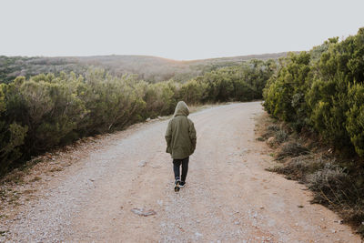 Rear view of woman walking on road against clear sky