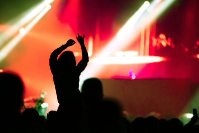 Rear view of silhouette of crowd with arms outstretched at concert. summer music festival concept