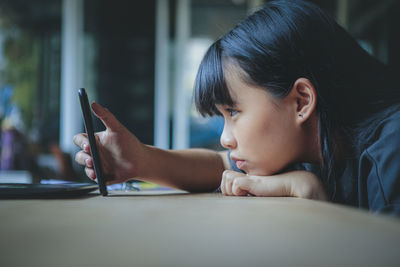 Young woman using mobile phone on table