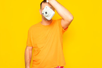 Midsection of woman wearing hat against yellow background