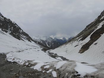 Snow covered mountains against cloudy sky