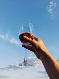 Midsection of man holding glass against sky