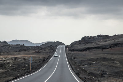 Empty road by mountain against sky