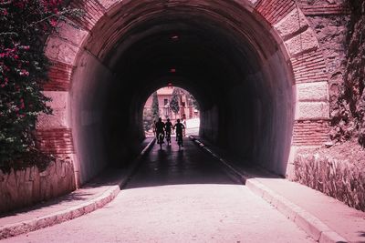 Rear view of people walking in tunnel